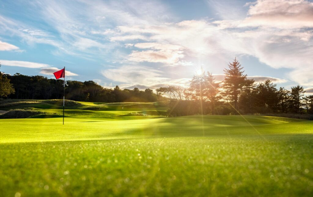 Golf course with flag at sunset
